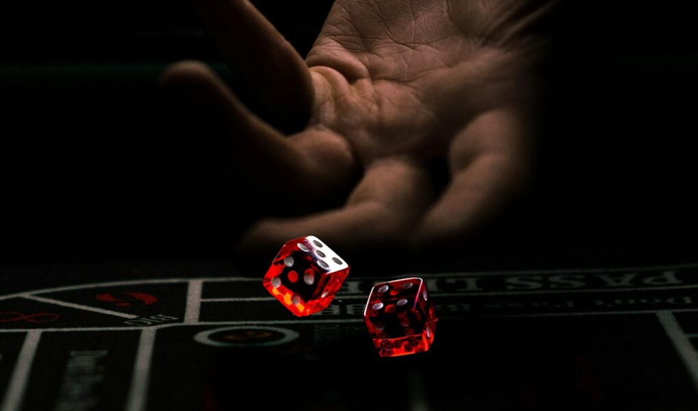 a hand with a finger pointing at a red and white dice
