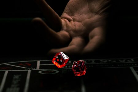 a hand with a finger pointing at a red and white dice