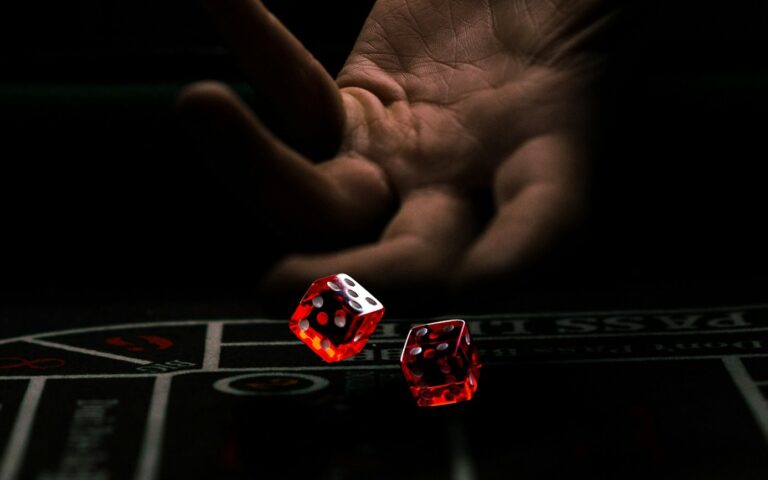 a hand with a finger pointing at a red and white dice